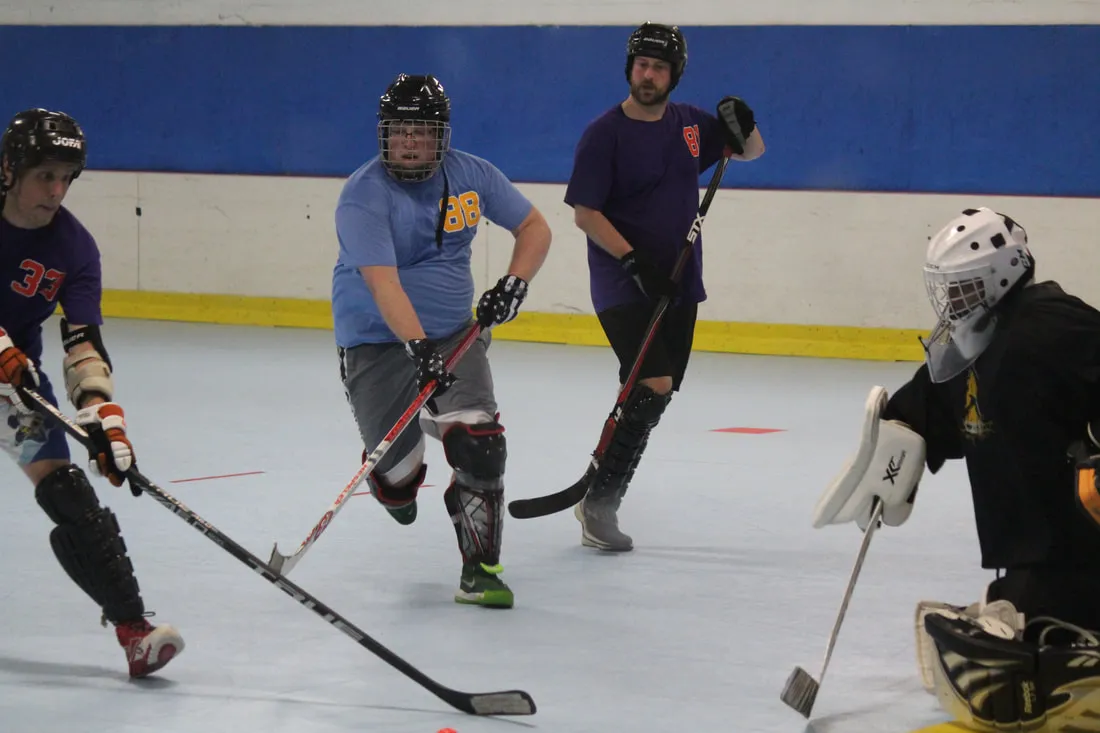 Adult dek hockey players chasing the ball in on the goalie at the Bridgeville HockeyPlex