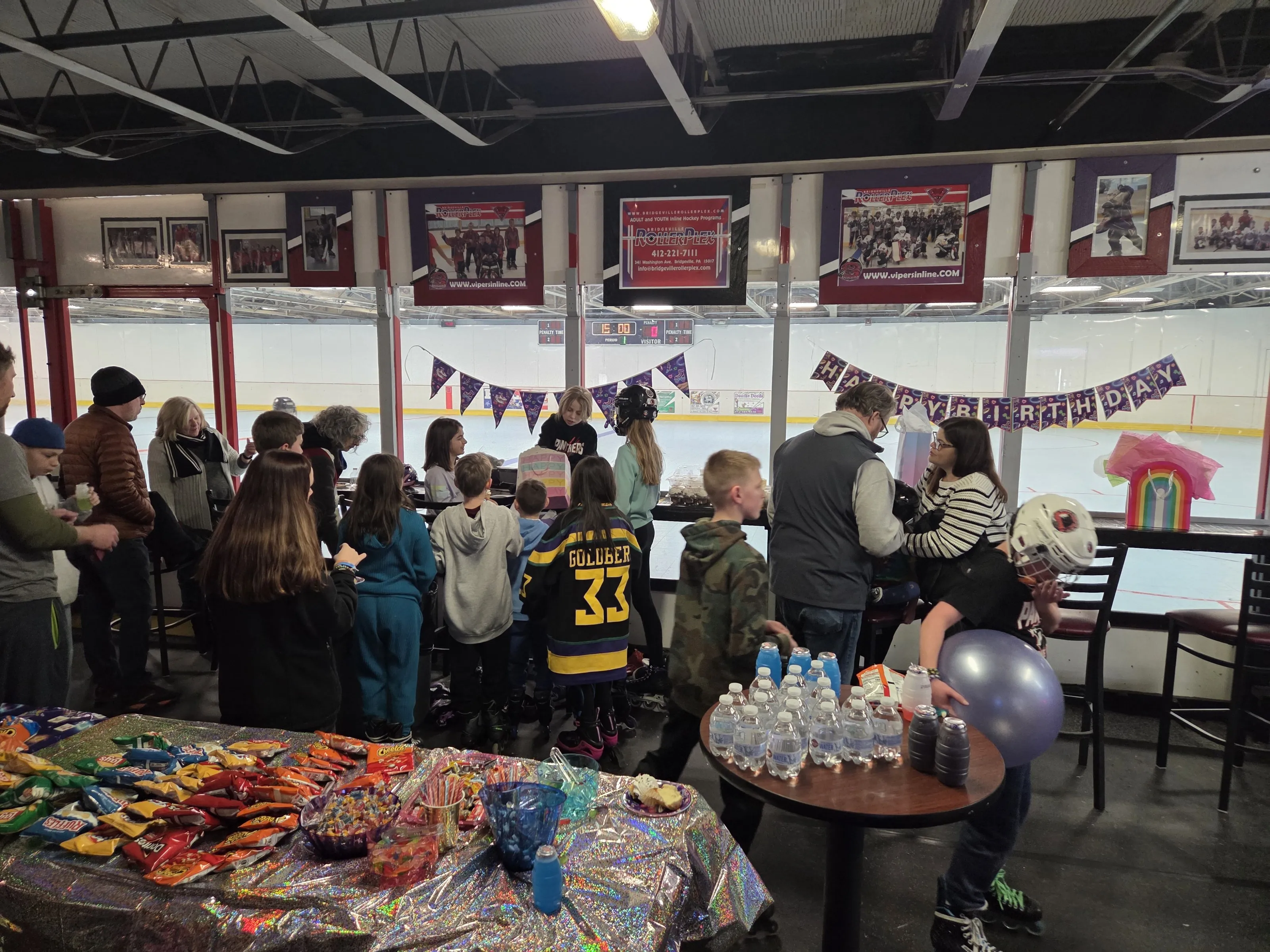A birthday party set up in the Main Hall at the Bridgeville HockeyPlex, with the rink and scoreboard visible through the glass