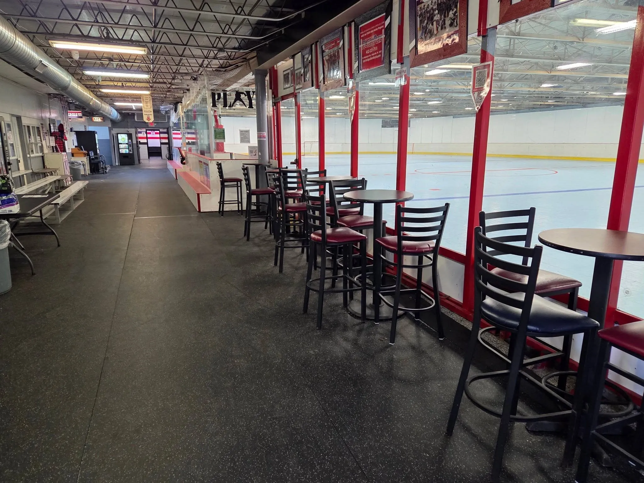 The concourse at the Bridgeville HockeyPlex, with high-top tables along the glass looking onto the rink