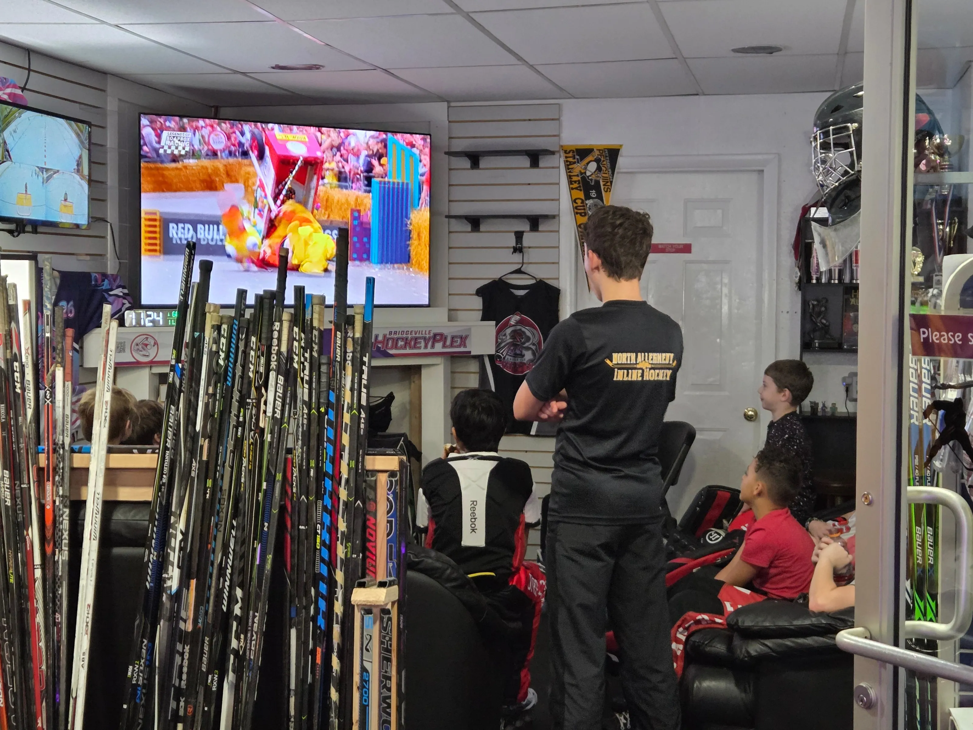 Inside the ProShop at the Bridgeville HockeyPlex, with racked sticks, a TV and players waiting