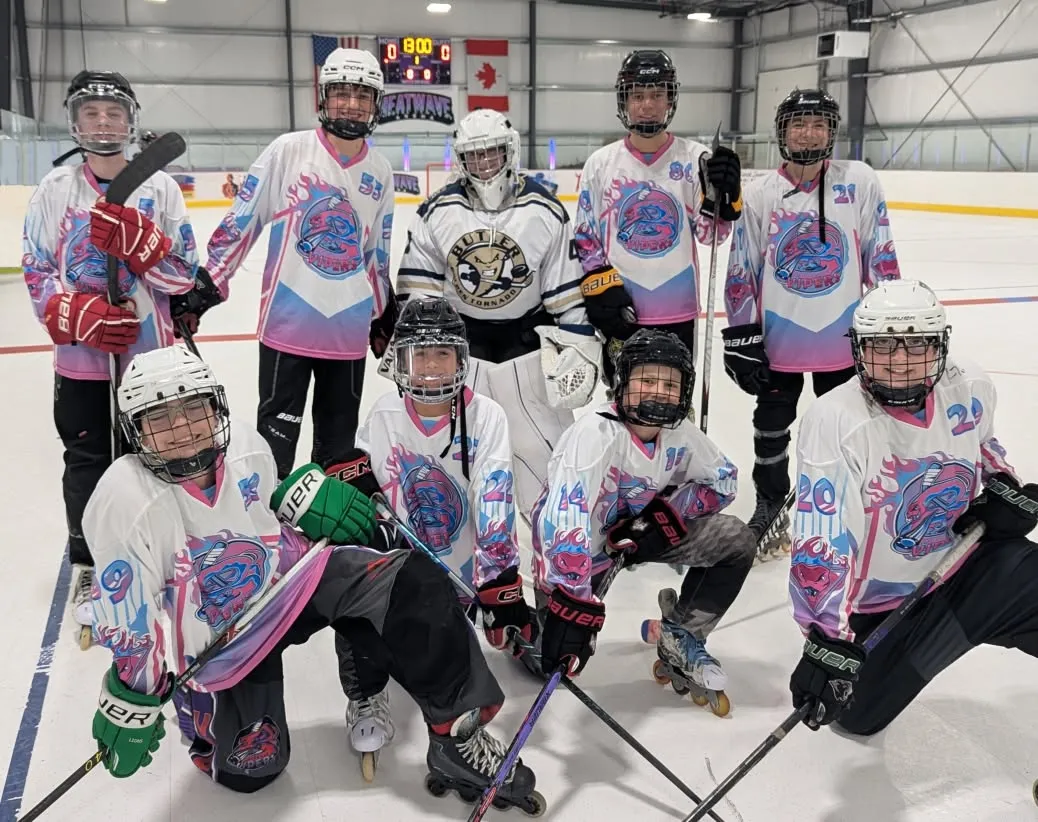 A Bridgeville Vipers travel team in their pink and blue jerseys with their goalie, posed on the rink